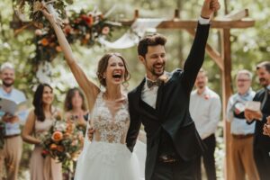 Coppia felice e vittoriosa il giorno del matrimonio che condivide la gioia con tutti gli invitati