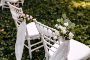sedie decorate con eucalipto e fiori bianchi nella cerimonia all'aperto