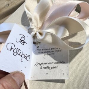 Particolare del tag realizzato in carta piantabile e stampato con i nomi degli sposi, la data del matrimonio, una frase tratta dal vangelo scelta dalla coppia, i ringraziamenti e - scritto a mano - il nome dell'invitato a cui è destinata la bomboniera.